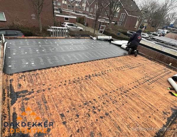 Dakdekker legt onderlaag op plat dak met houten constructie in Drenthe