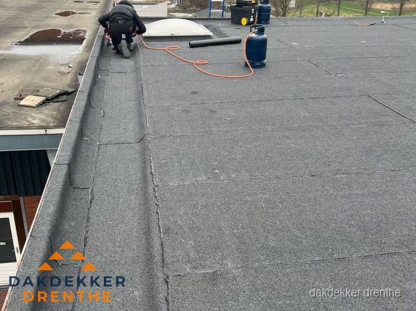Dakdekker repareert bitumen dakbedekking op groot plat dak in Drenthe
