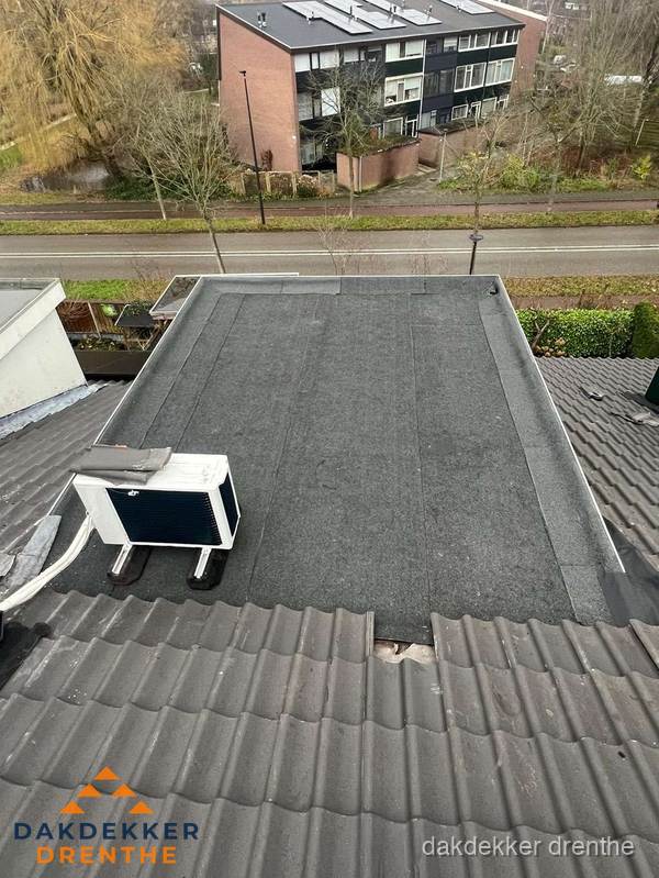 Plat dak inspectie met bitumen bedekking naast schuin pannendak in Drenthe