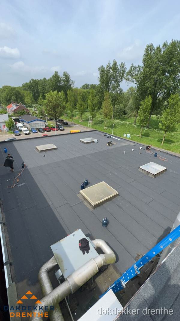 Dakdekker aan het werk op groot plat dak met bitumen in Drenthe