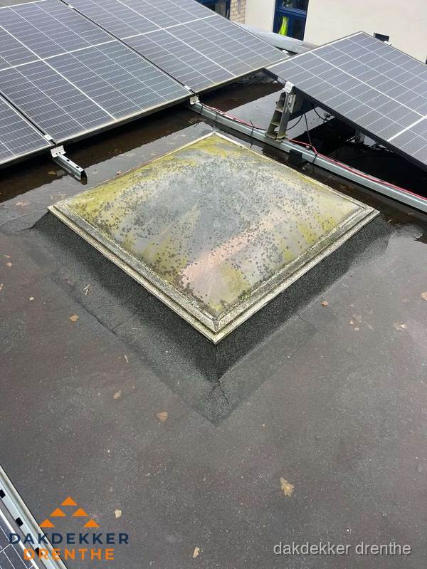 Vervuilde lichtkoepel op plat dak met zonnepanelen in Drenthe